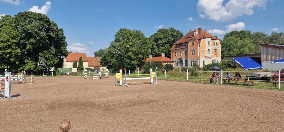Springplatz mit aufgebauten Hindernissen und Bäumen im Hintergrund
